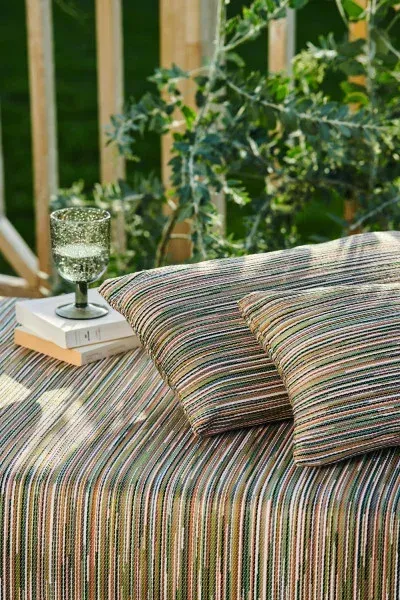 Détail d'un coussin d'extérieur Casamance Amalfi dans un jardin, ambiance terrasse et nature.