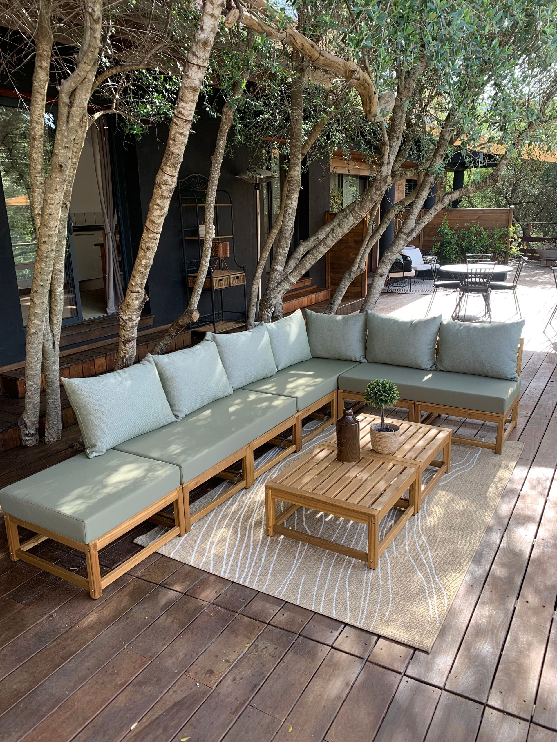 Coussins extérieurs vert d'eau sur mesure pour une belle structure d'angle en bois dans un jardin ensoleillé.