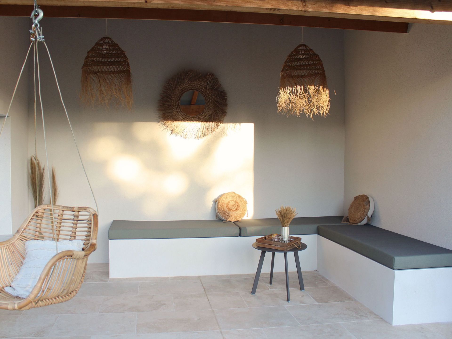 Coussin d'assise gris sur mesure pour une banquette maçonnée avec des luminaires en paille au-dessus.
