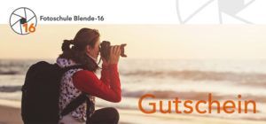 Jetzt Blende-16 Fotokurs Gutschein online kaufen Eine Fotografin mit Rucksack fotografiert am Meer. Blende-16 Fotokurs Gutschein zum Verschenken.