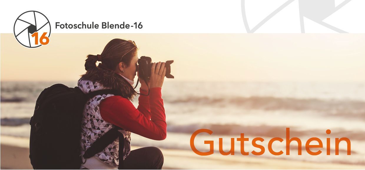 Eine Fotografin kniet im warmen Licht am Strand und blickt konzentriert durch den Sucher ihrer Kamera. Sie fotografiert in die Weite des Meeres, was die Atmosphäre und den kreativen Freiraum eines Blende-16.de Fotokurs-Gutscheins symbolisiert.