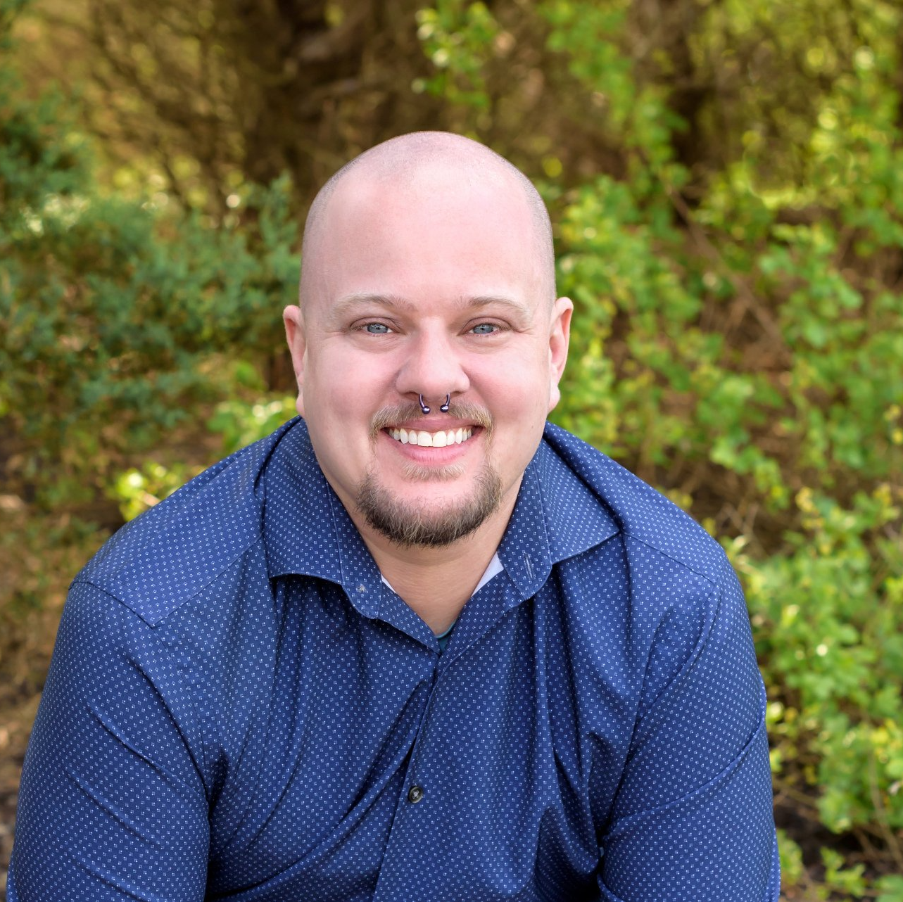 Image of Daniel, A bald white man smiling in a blue shirt