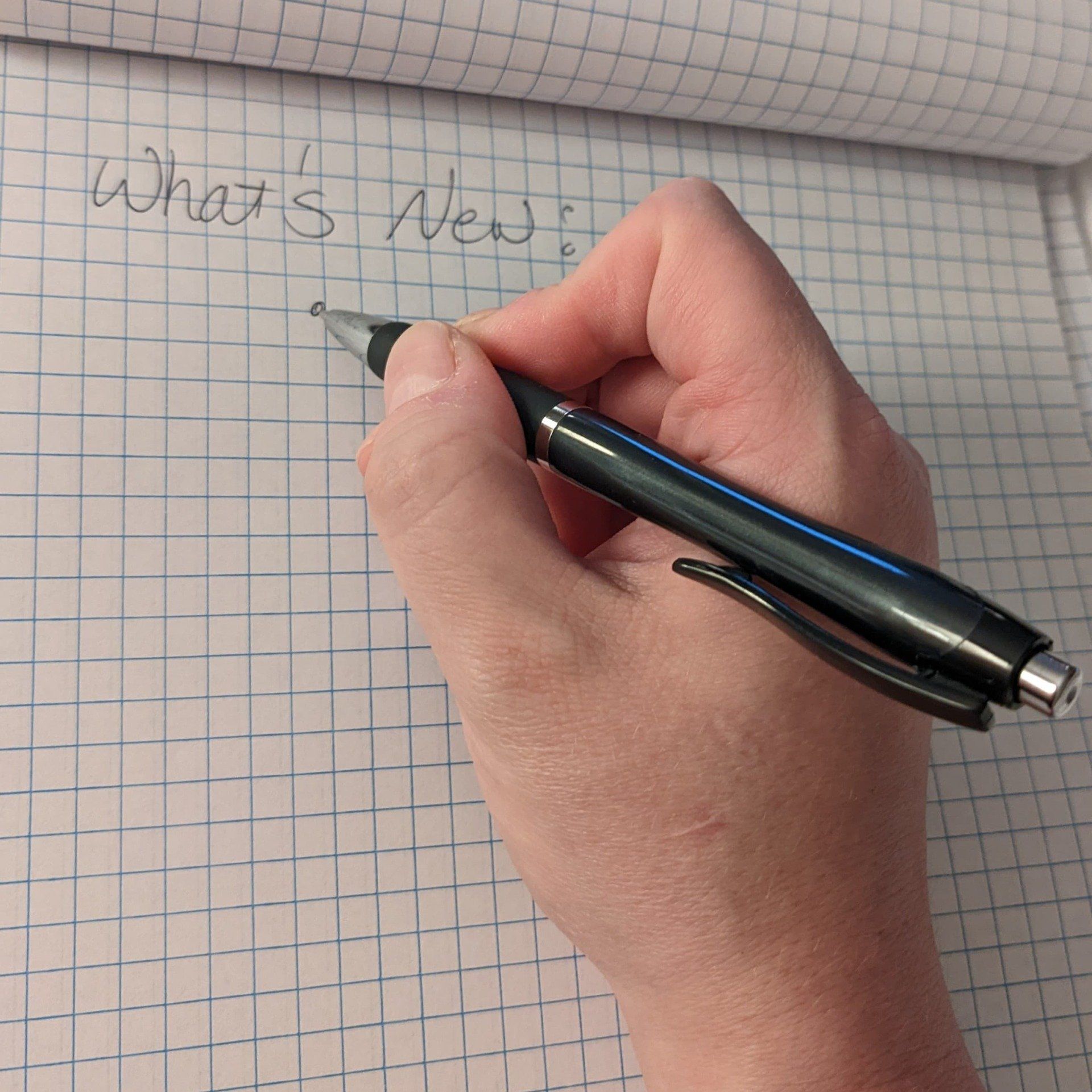 Daniel's right hand holding a pen on a grid paper: