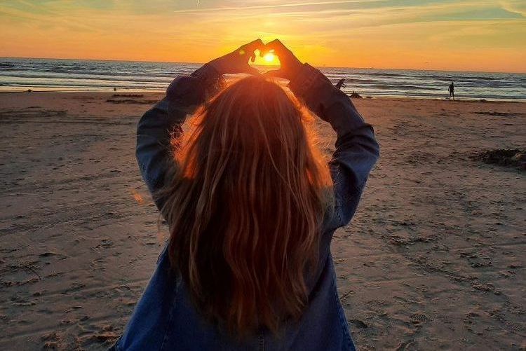 Happy Familiytime Familiencoaching und Emotionscoaching. Kind steht am Strand und hält Hände in Herzform hoch.