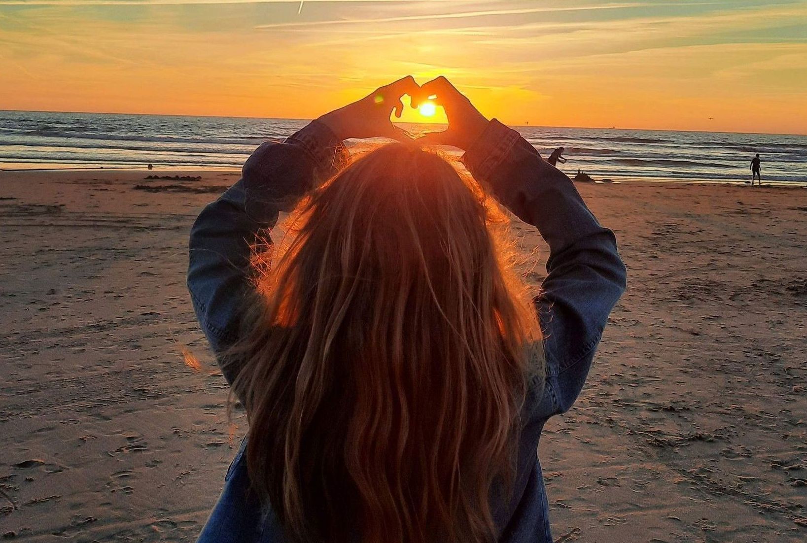 Happy Familiytime Familiencoaching und Emotionscoaching. Kind steht am Strand und hält Hände in Herzform hoch.