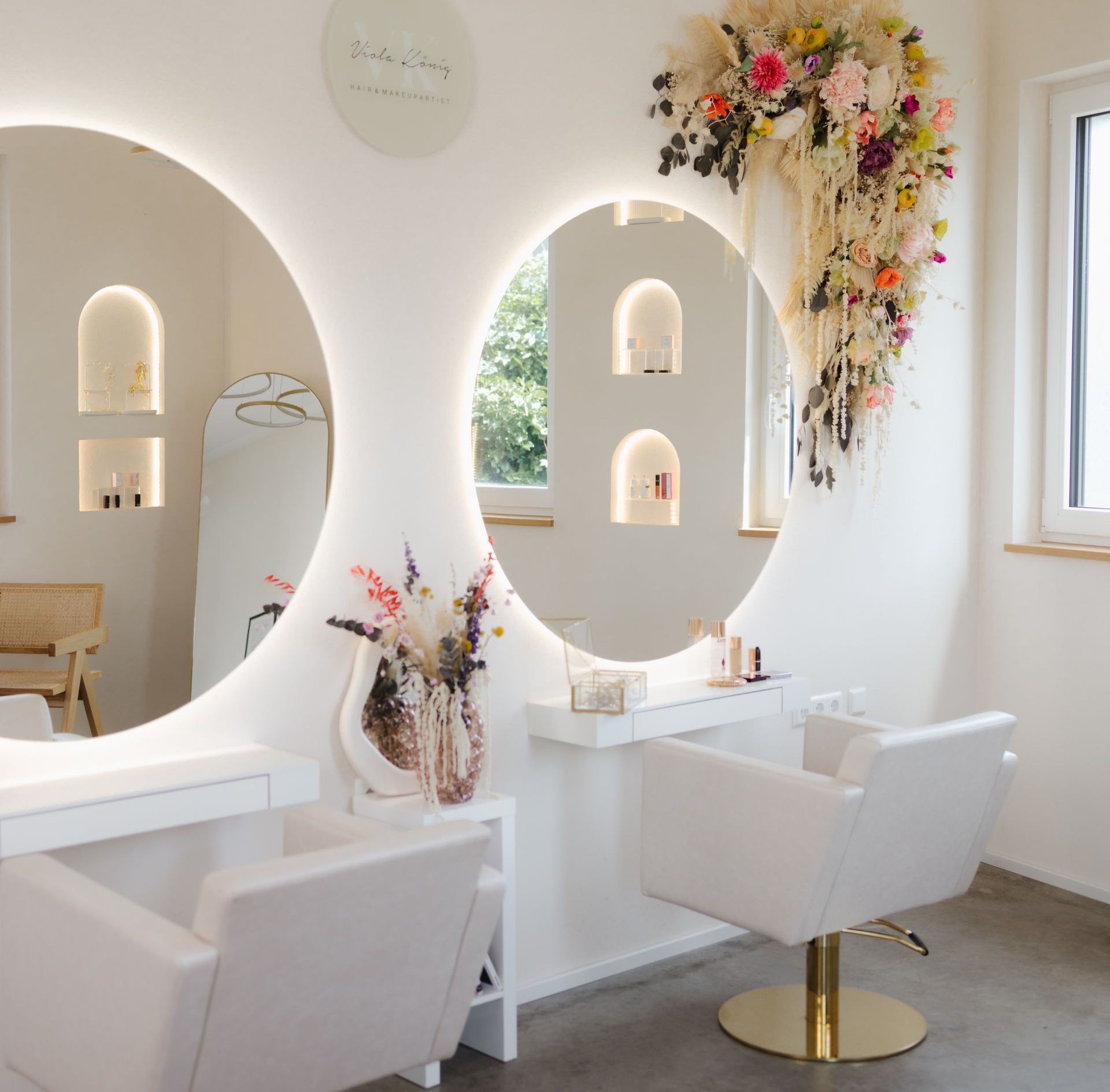 Viola Königs Hair & Make-Up Studio von innen, große Wand mit Blumenschmuck und eleganten Spiegeln.