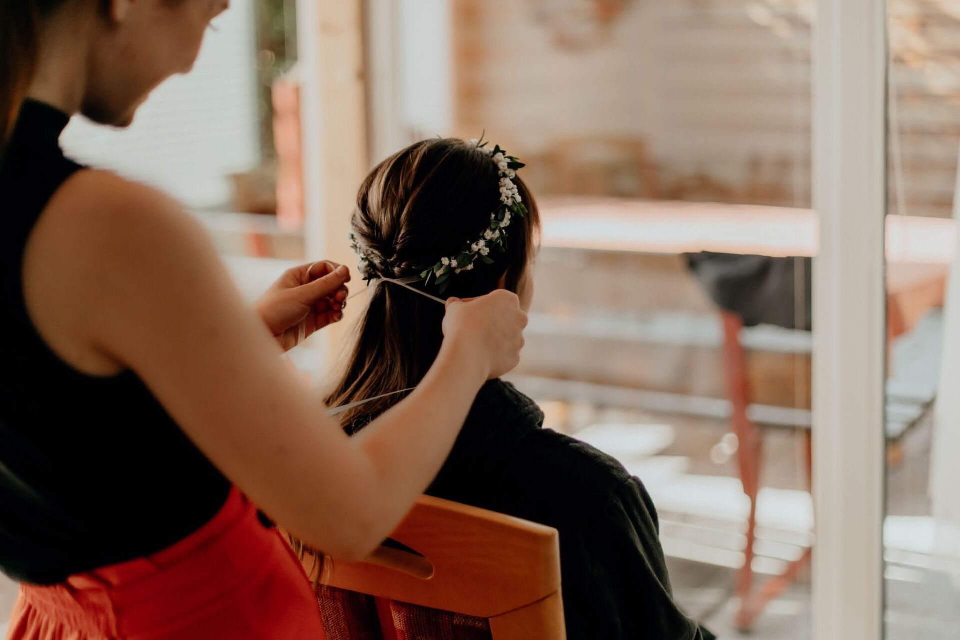 Brautstyling vor Ort: Stylistin setzt Haarschmuck in geflochtene Brautfrisur für die Hochzeit