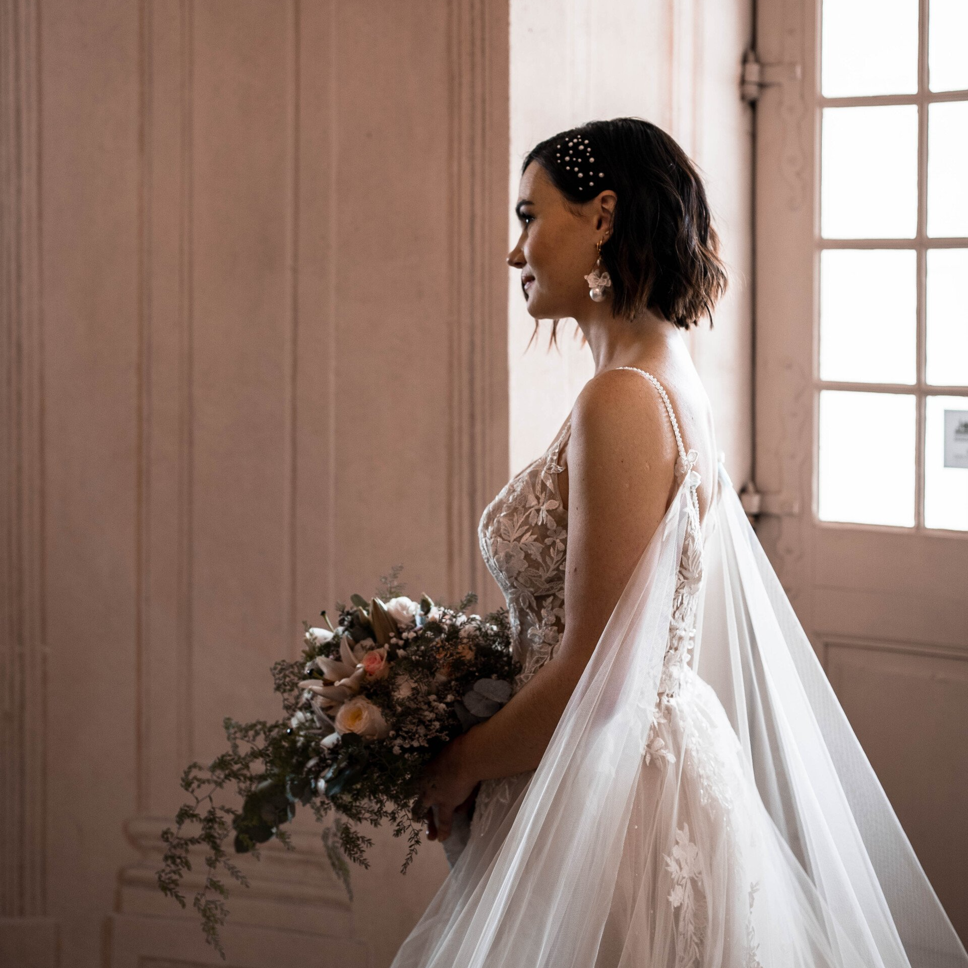 Braut mit kurz gestyltem Haar und dezentem Make-up in elegantem Innenraumlicht.