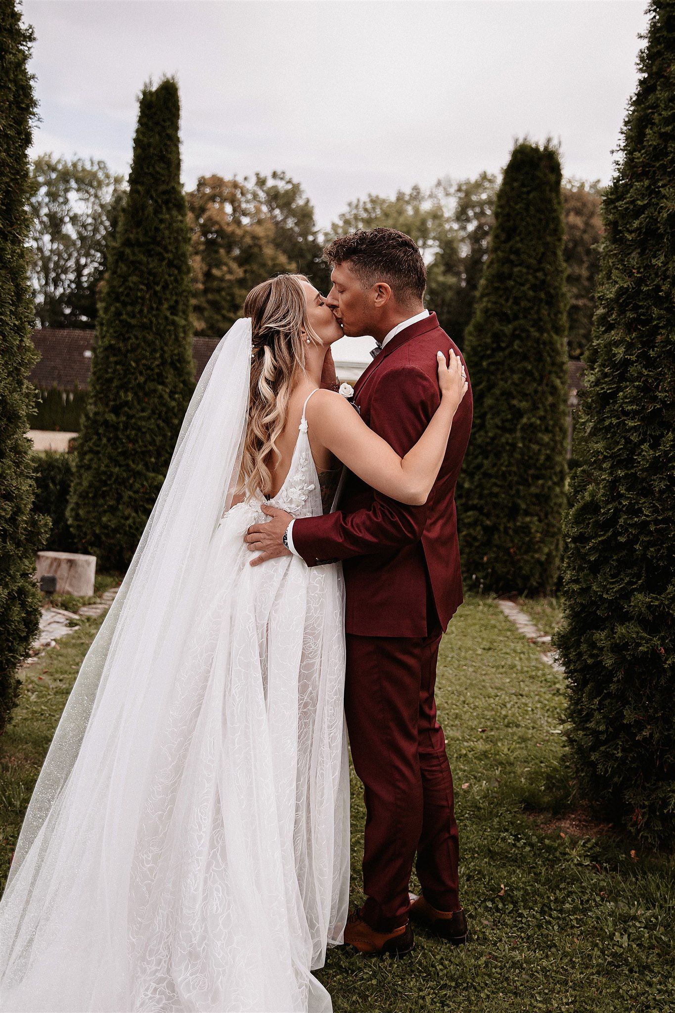 Brautpaar Kuss im Park zwischen Bäumen, romantischer Hochzeitsmoment