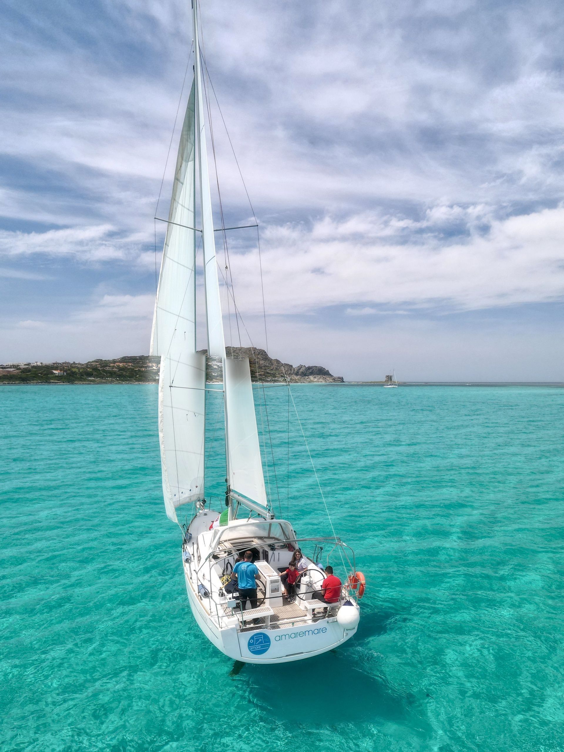 La barca a vela Duck con la torre della Pelosa sullo sfondo
