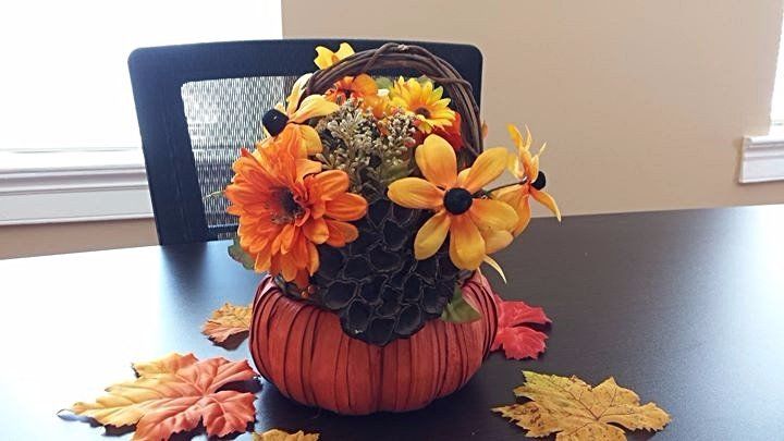 Pumpkin center piece with fall flowers and leaves.