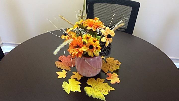 Pumpkin center piece with fall flowers and leaves.