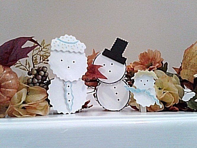 Our Mascots, snow people, dressed for the summer season on a mantle decorated for fall.