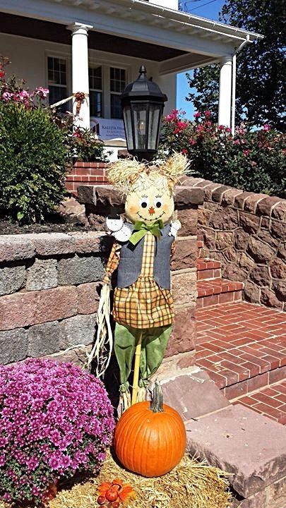 Girl scare crow with bail of hay, pumpkin, a mum and sunflower.
