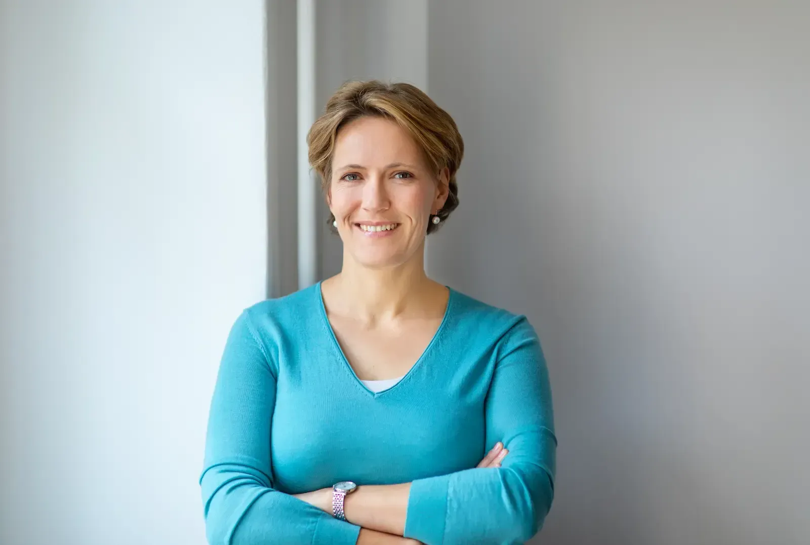 Ulrike Strohscheer, lächelnd und stehend in tuerkisfarbenem Pullover.