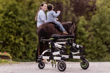 Kind mit Gehbehinderung reitet auf Pony