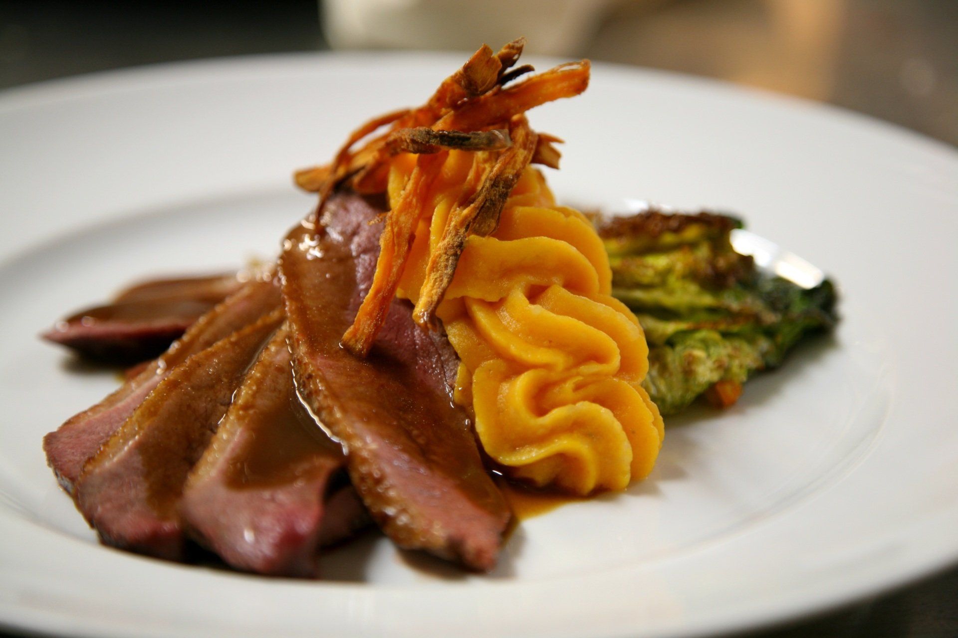 drei dünne Scheiben Lammkeule, gebratener Romanasalat und eine Rosette Süßkatoffel Pürree