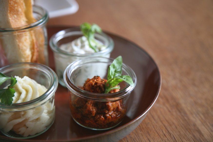 Kräuterquark und Pilzaufstrich in kleinen Weckgläschen auf einem Teller arrangiert