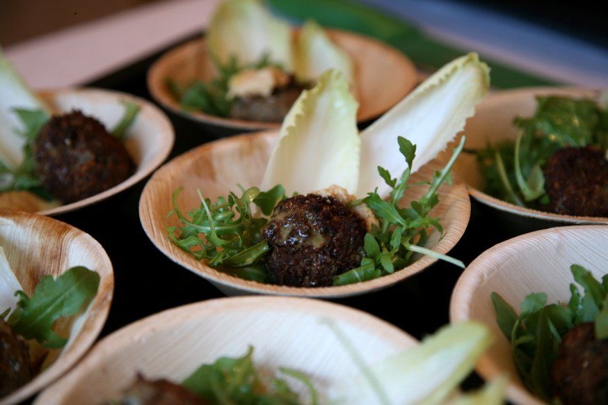 Fleischbällchen mit einem Chicoreeblatt und Salatgarnitur in einem Palmblattschälchen