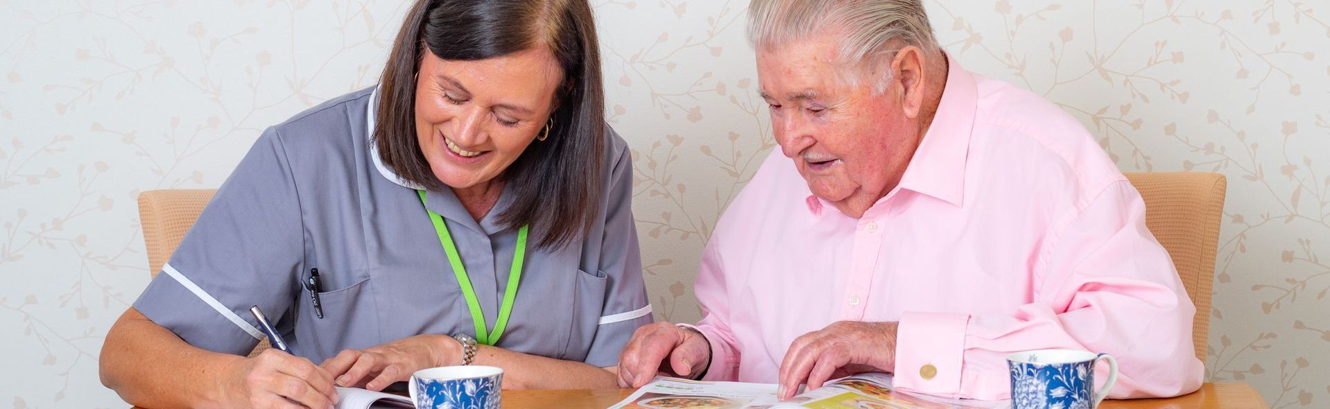 Gentleman and carer having a cuppa whilst filling in some paperwork