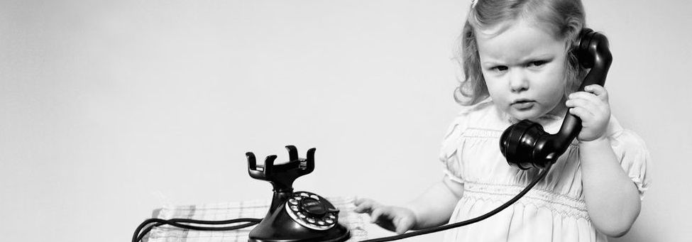 Black and white picture of a cute little girl using an old fashioned phone to illustrate 'getting in touch'