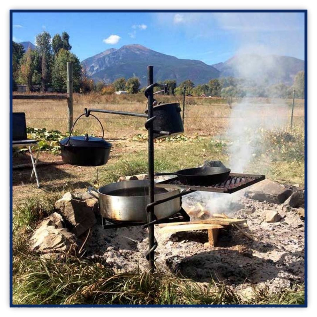 A portable outdoor cooking gear setup showcasing the grill's easy placement over a campfire.