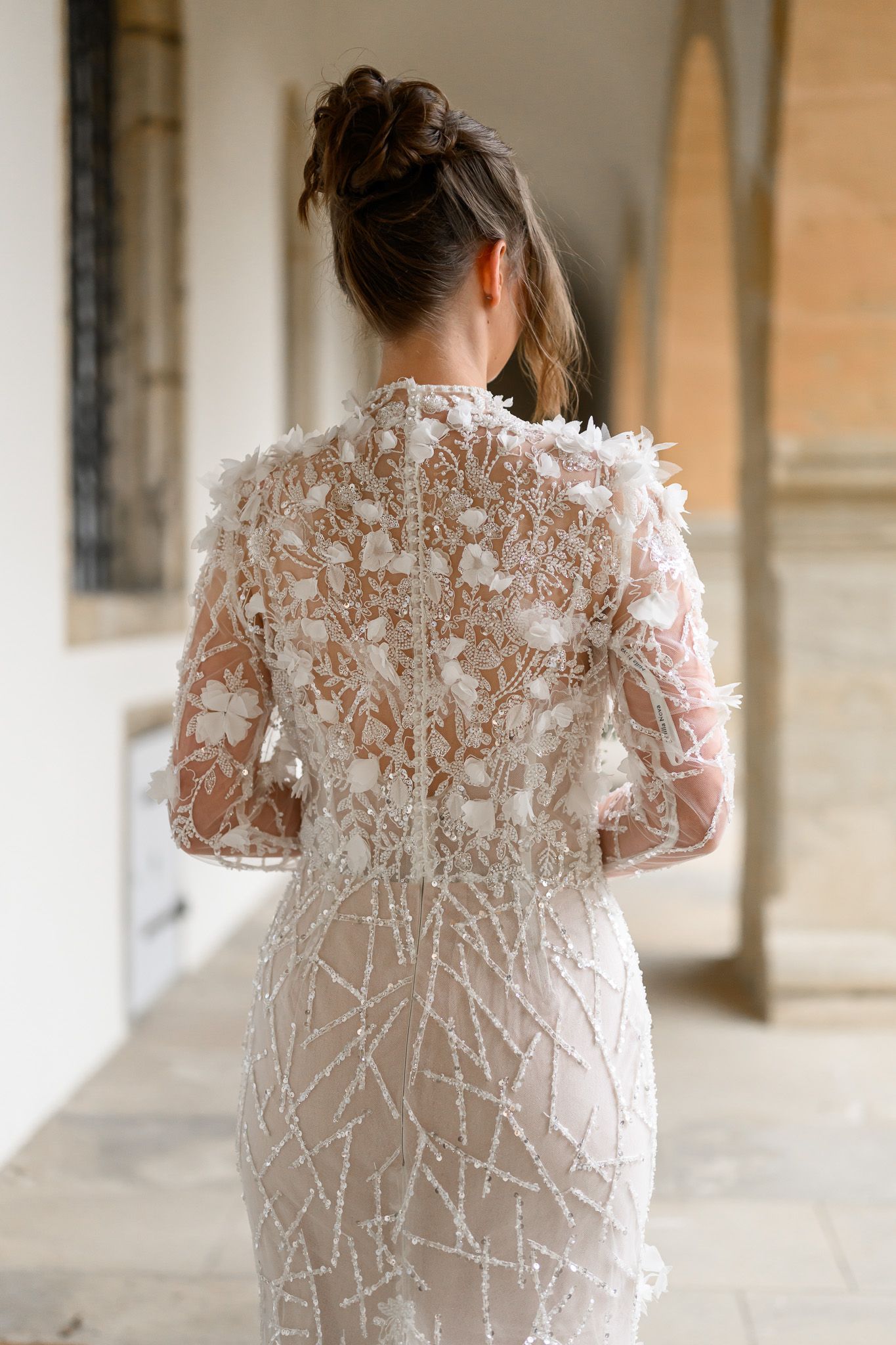 Detailaufnahme des kunstvoll bestickten Brautkleids mit floralen Applikationen im historischen Arkadengang der Altstadt Bamberg.