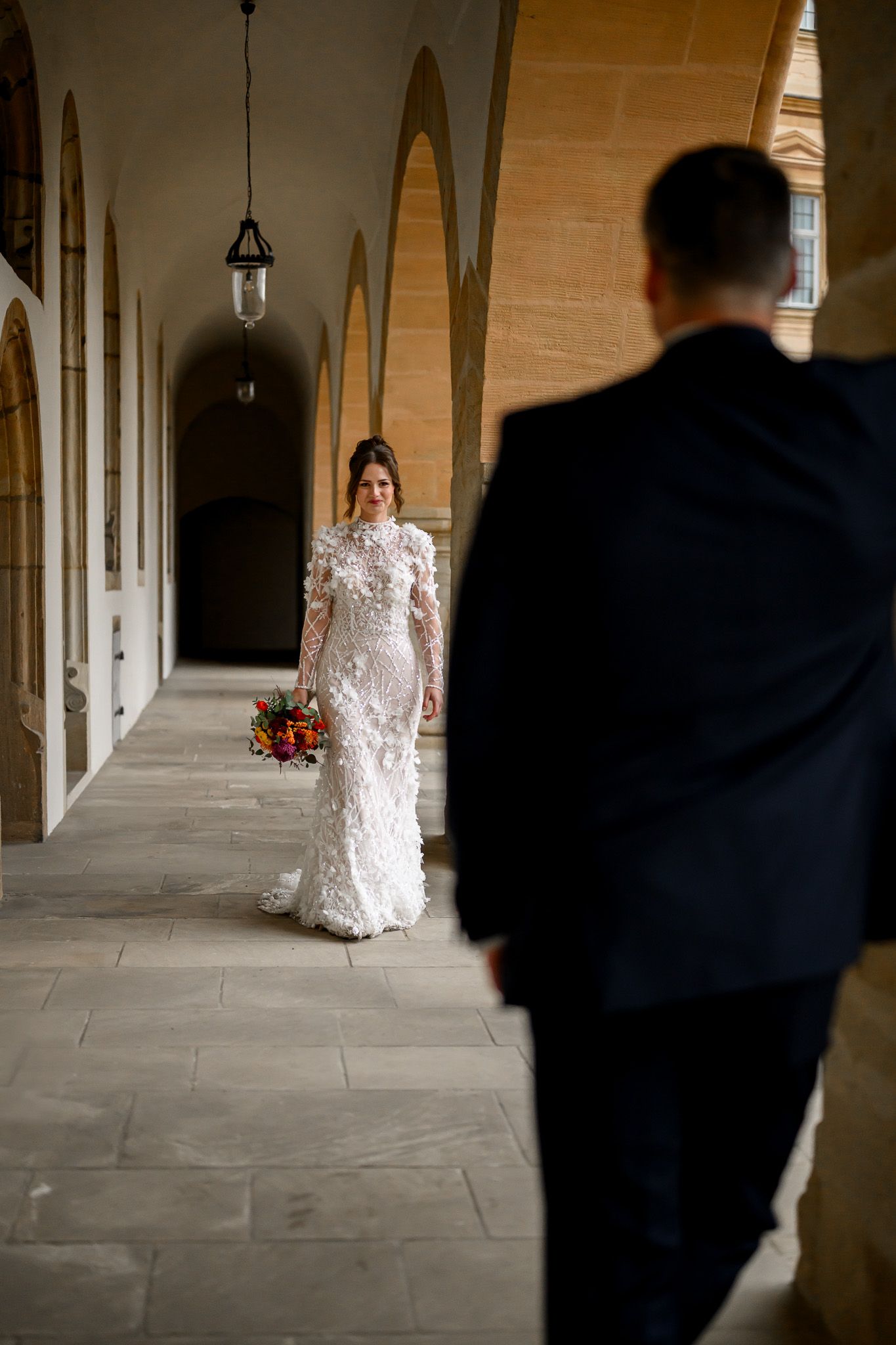 Emotionaler First Look in der Altstadt Bamberg: Die Braut im eleganten Spitzenkleid geht im Arkadengang auf ihren Bräutigam zu – festgehalten von Thomas Freitag Fotografie.