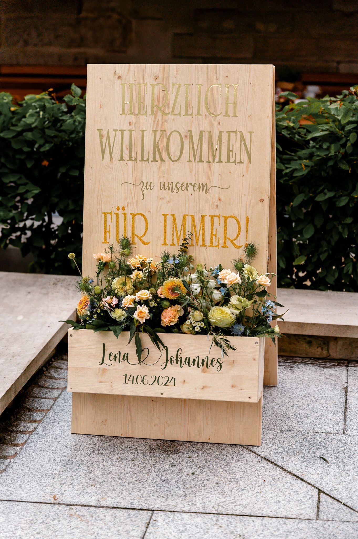 Willkommensschild zur Hochzeit von Lena und Johannes mit floraler Dekoration aus Rosen, Disteln und Wildblumen.