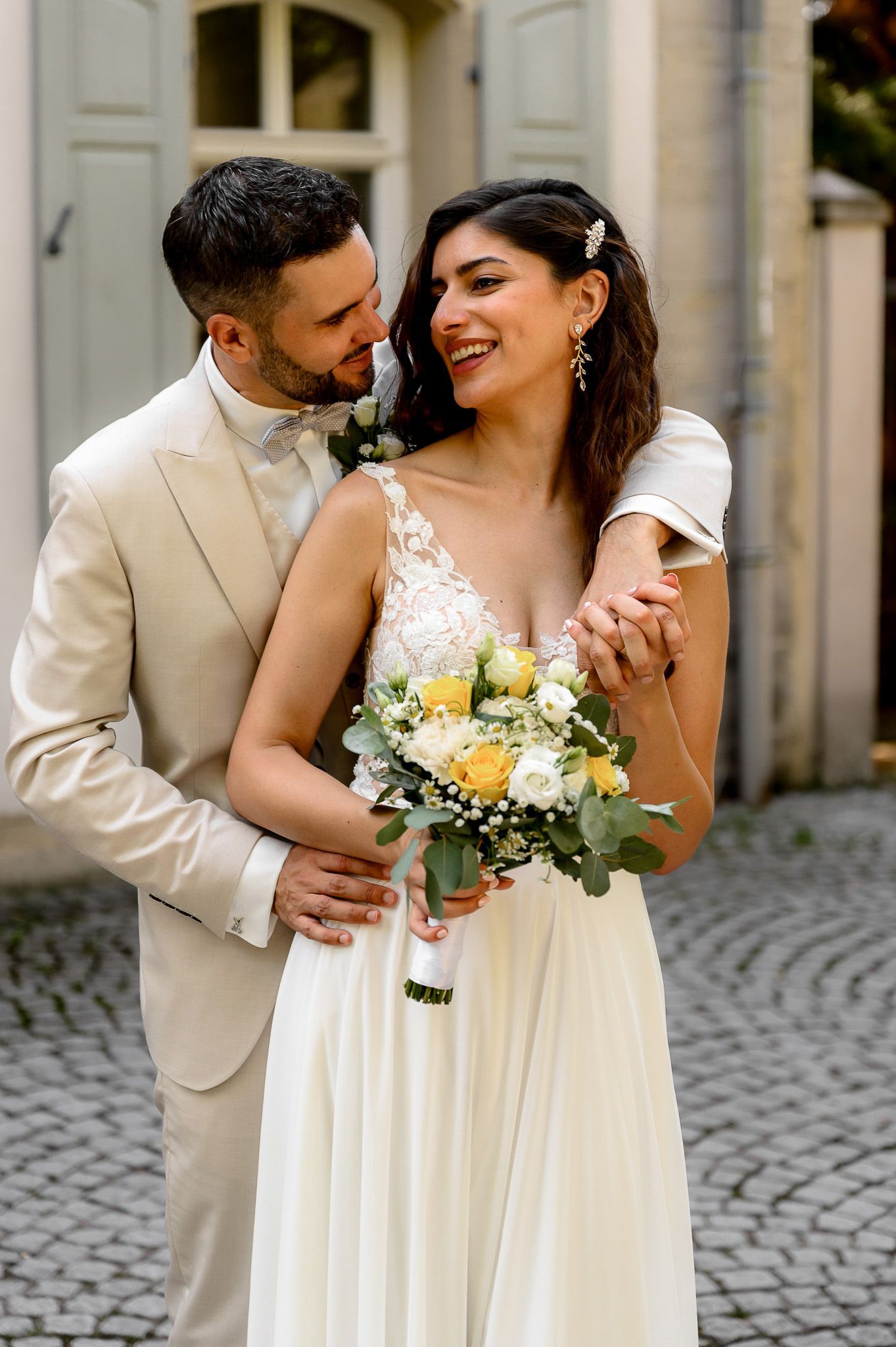 Braut und Bräutigam umarmen sich beim Standesamt Coburg, beide lachen verliebt.