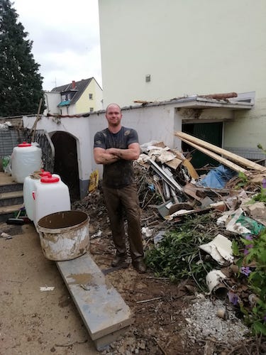 Wasserschäden Beseitigung im Ahrtal mit unserer beteitigung. Ein Mitarbeiter von uns steht vor einem Haufen möbel die entrümpelt werden.