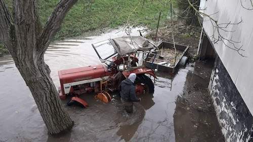 Ein Traktor mit Anhänger der im Wasser steht und aus der Garage die voll Wasser stand alles entrümpelt wurde.