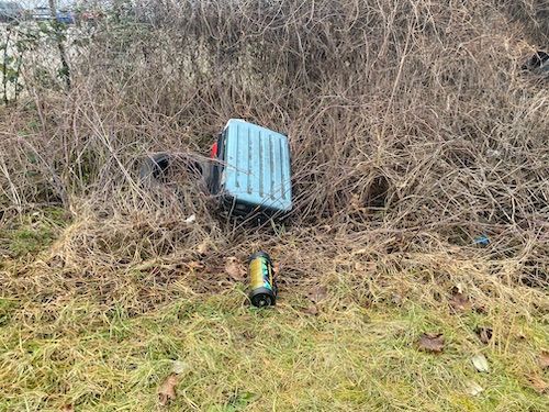 Illegale Müllentsorgung mit Koffer und Abfall an Grundstücksrand