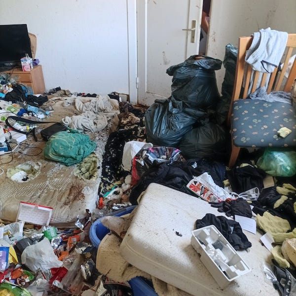 Ein verdrecktes Bett. Matratze total dreckig und aufgerissen mit vielen Müllsäcken um das Bett.