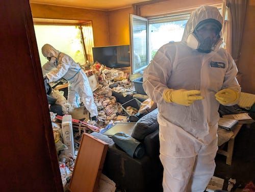 Das team mit Masken bei der Arbeit. mitten in den Ablagerungen von Abfällen, Haushaltsgegenständen und Verpackungen vor der Räumung.