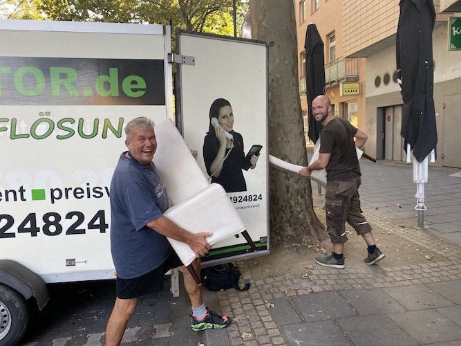 Gerald Molitor und Lukas tragen zwei alte Stühle in das Entrümpelungafahrzeug