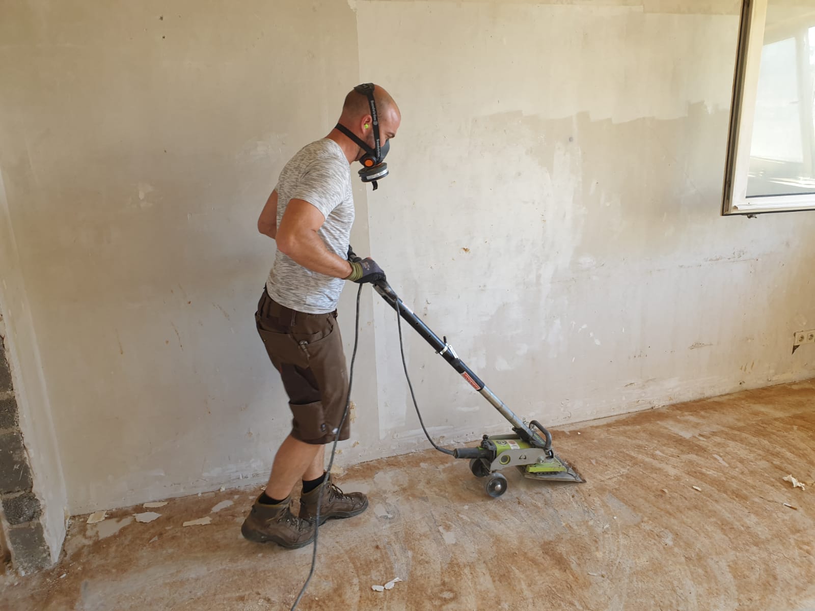 lukas kreus beim entfernen von einem verklebten teppichboden mit einer spezialmaschine für die teppichbodenenfernung, in einer haushaltsauflösung in taunusstein.