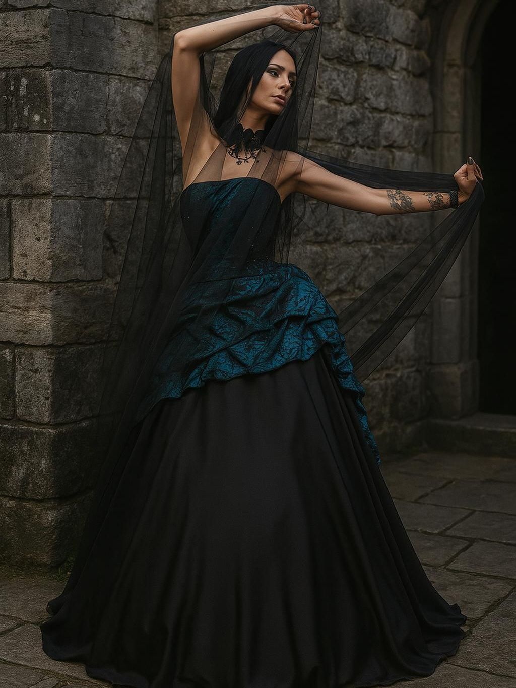 Eine Frau steht seitlich vor einer alten Steinmauer mit einem hohen Torbogen. Sie trägt ein schulterfreies Kleid im Victorian Art Style mit einem weit ausfallenden schwarzen Rock. Das Oberteil und der obere Rockteil sind in tiefem Petrol mit schwarzem Brokatmuster gestaltet, darüber liegt ein leichter schwarzer Tüllschleier, den sie mit beiden Händen seitlich ausbreitet. Ihr langes, schwarzes Haar fällt glatt über die Schultern. Sie trägt ein auffälliges schwarzes Halsband mit Schmuckelementen sowie dunkles, ausdrucksstarkes Make-up. Auf ihren Armen sind tätowierte Motive sichtbar. Die Szenerie wirkt dramatisch, geheimnisvoll und elegant.
Dieses Outfit ist im Gothic-Style gehalten und erhältlich im Dark Dream Atelier für Gothic- und Steampunk-Mode in Gründau für Stuttgart