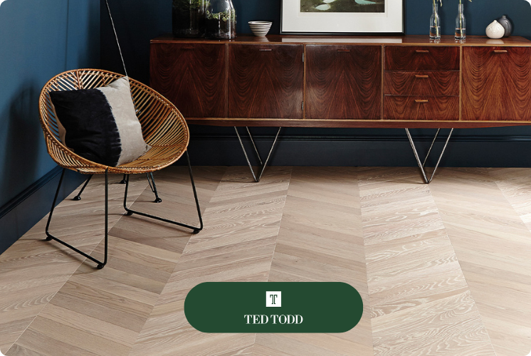 Ted Todd Create flooring in a chevron pattern, a small wicker chair, and a mud brown sideboard