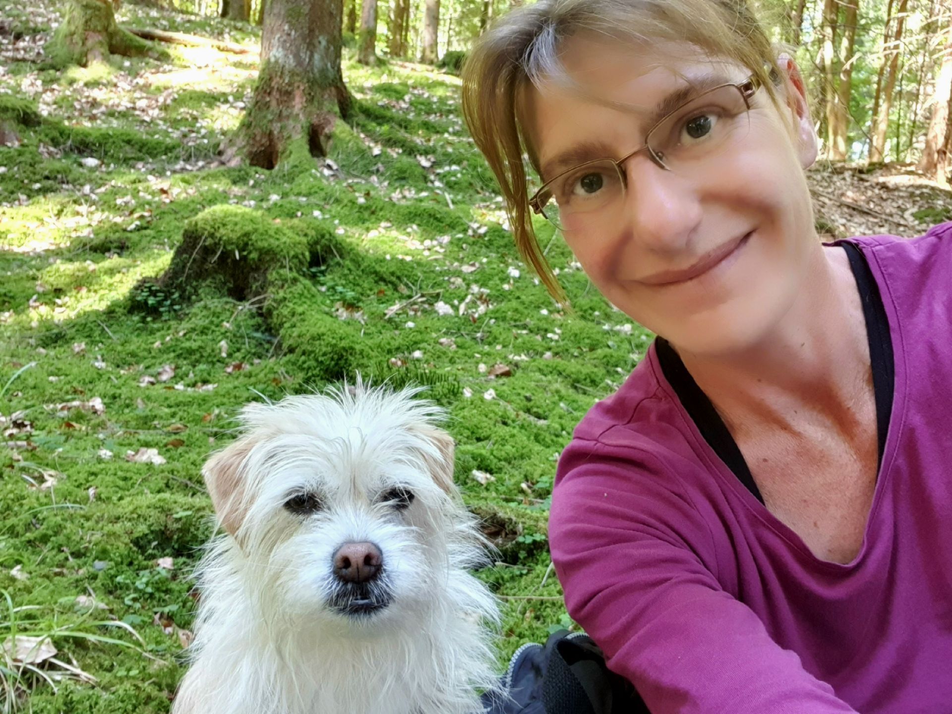 Sabine Hörnicke mit Trüffelprofi Milly sabine hoernicke mit weißem hund milly im moosigen Wald.
