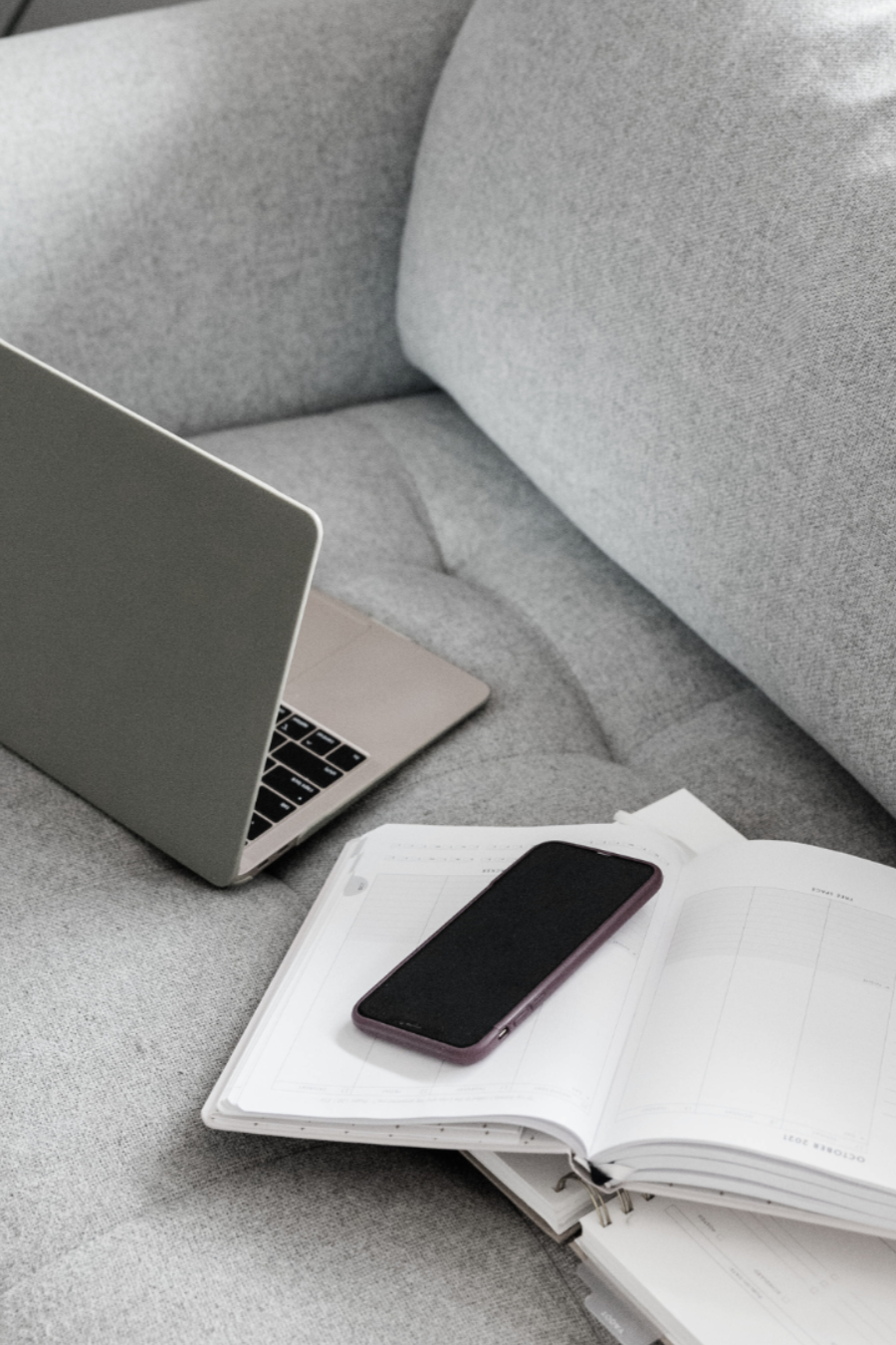 Laptop ind Handy stehen auf einem grauen Sofa