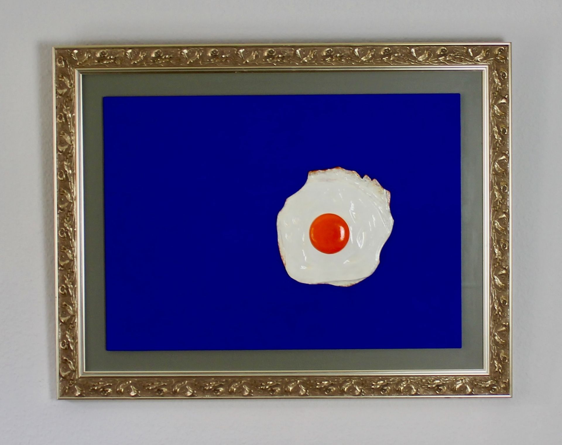 Plastisch gestaltetes Spiegelei auf ultramarinem Grund in einem silberfarbenen Rahmen von Künstler Oliver Pohl aus Haste im Schaumburger Land