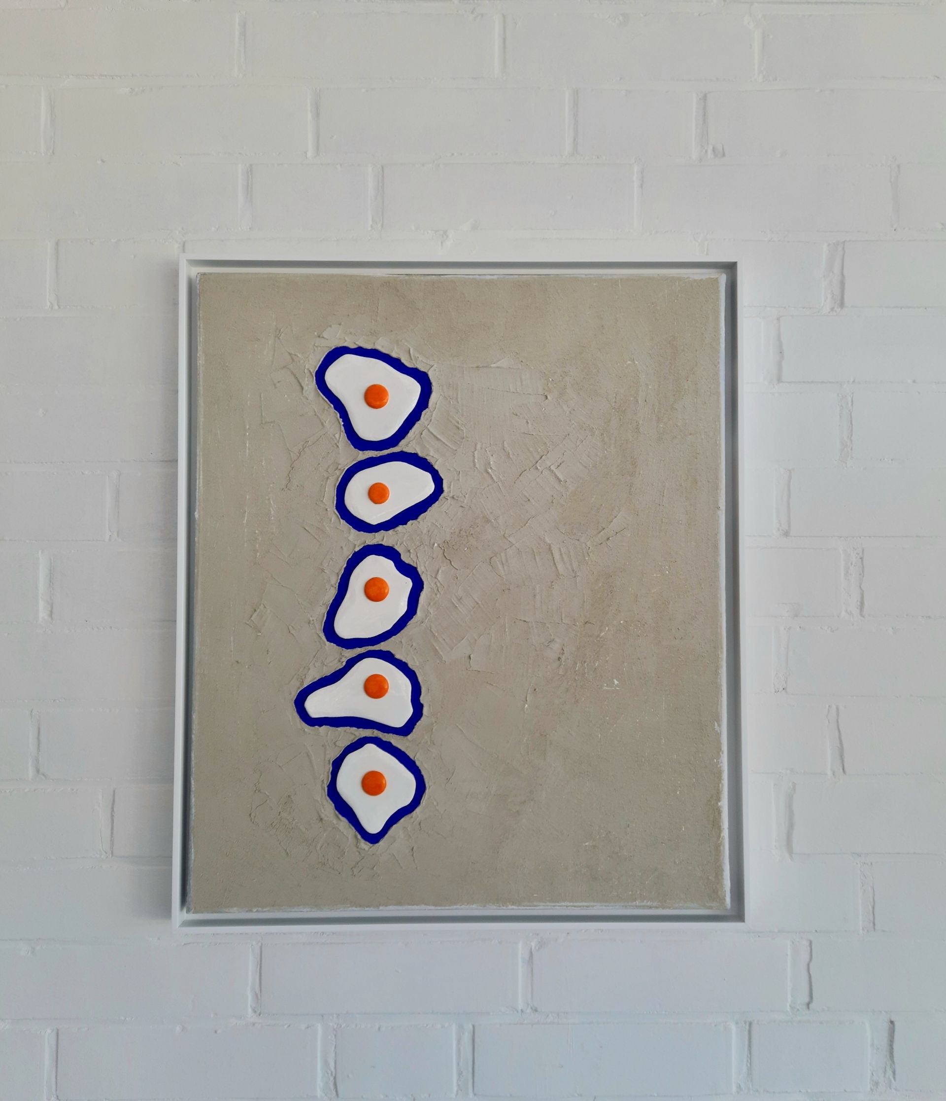 Wandbild mit sandfarbener Leinwand und fünf plastischen Spiegleiern.