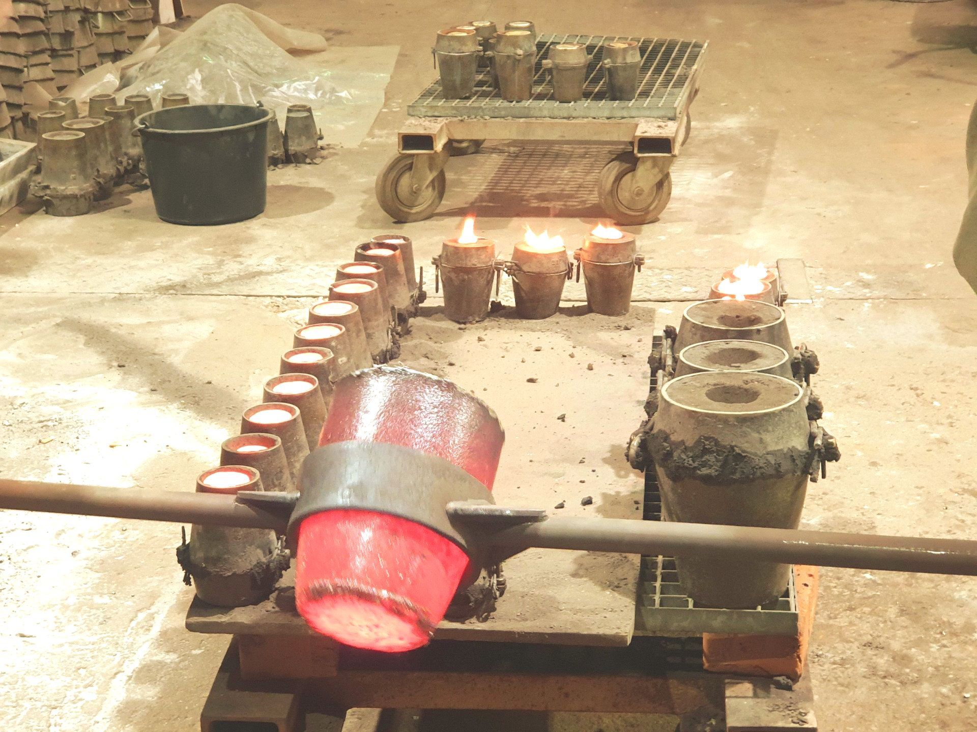 Das Bild zeigt Mitarbeiter beim Bronzeguss. Sie gießen 1160 Grad heiße, glühende Bronze in die vorbereiteten Formen.