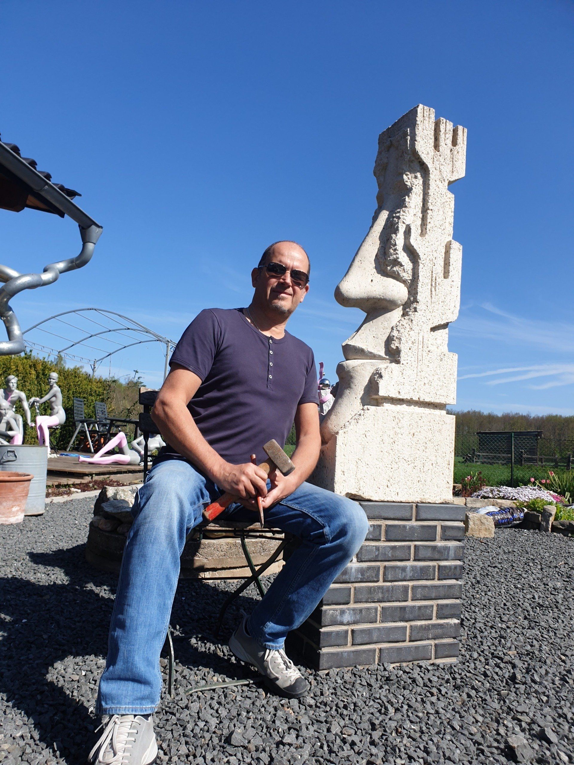 Das Bild zeigt den Bildhauer und Künstler Oliver Pohl aus Haste bei Wunstorf vor einer großen Steinskulptur.