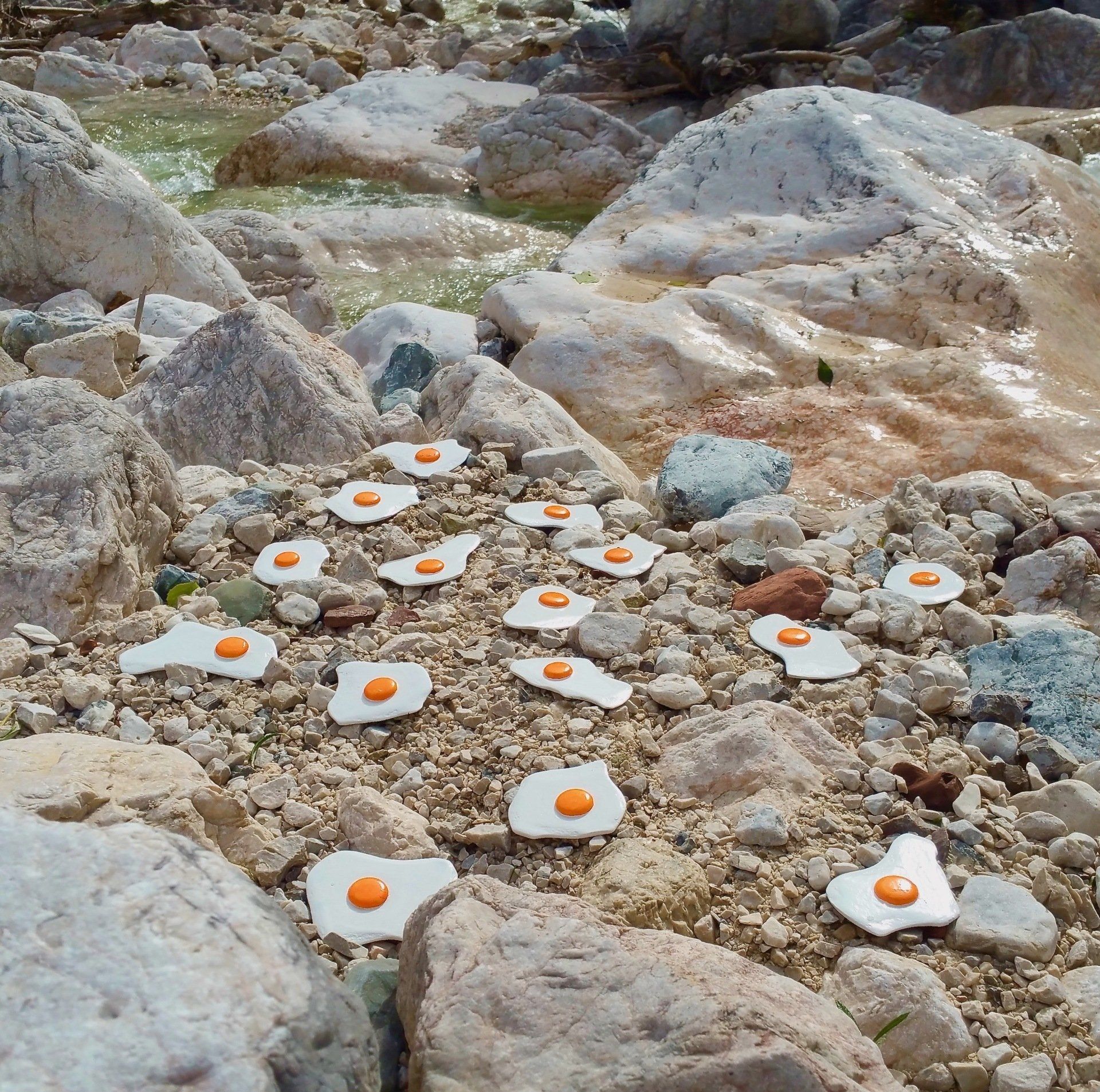 Das Bild zeigt Spiegeleier-Skulpturen von Bildhauer und Künstler Oliver Pohl aus Haste bei Wunstorf am Steinhuder Meer. Das Foto ist an einem Gebirgsbach bei Berchtesgaden entstanden.