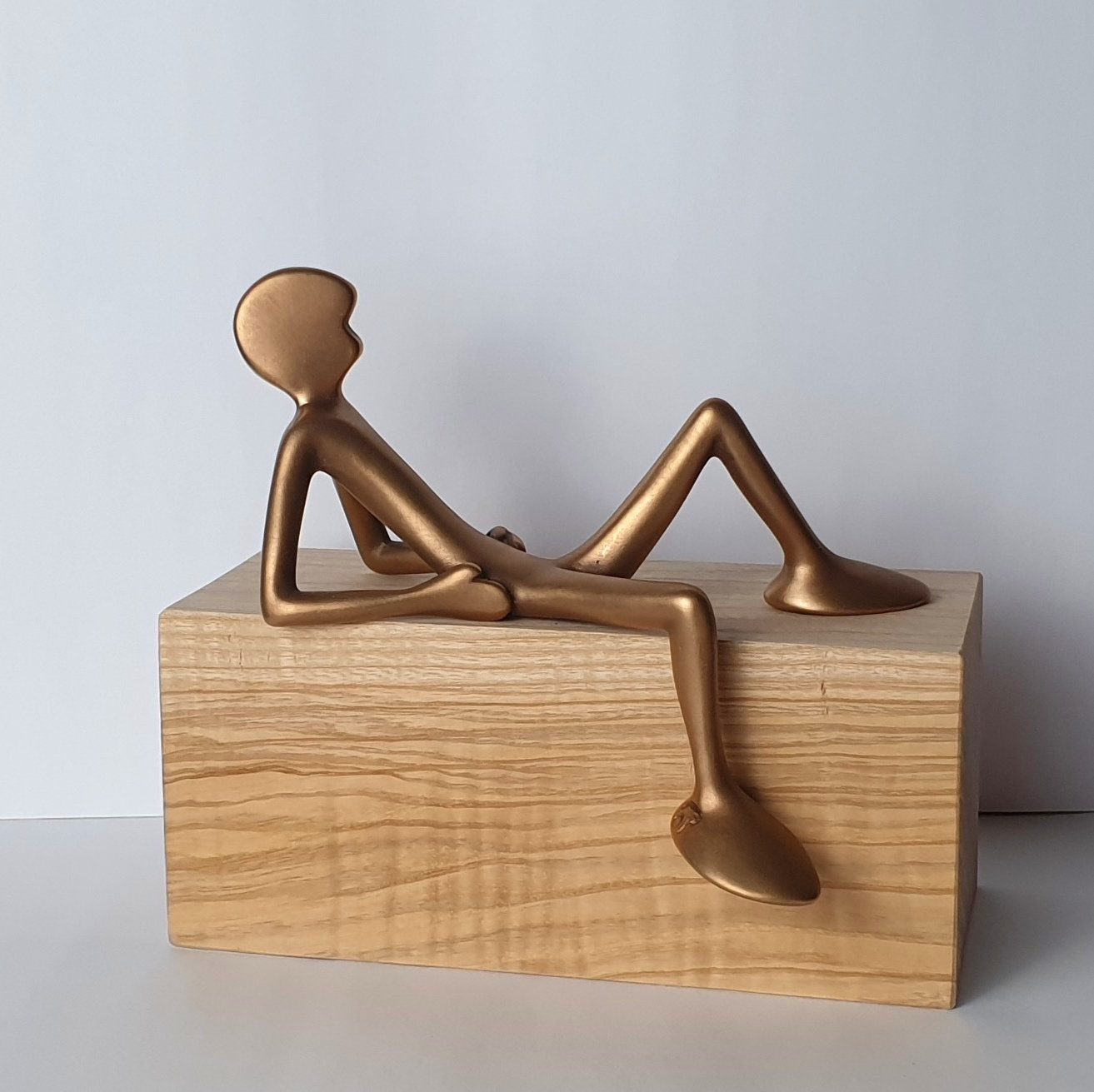 FRIENDs No 3 Kleine Bronzefigur der Serie Friends von Bildhauer Oliver Pohl auf einem hellen Eschenholzsockel sitzend