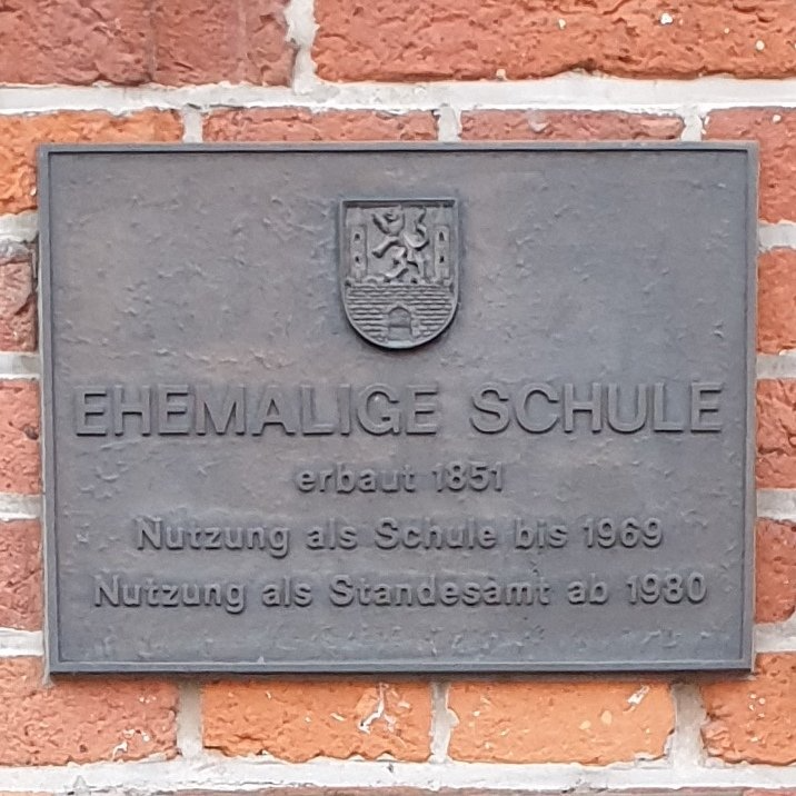 Das Bild zeigt eine Bronzetafel für ein historisches Gebäude in Neustadt am Rübenberge, gefertigt von Bildhauer Oliver Pohl