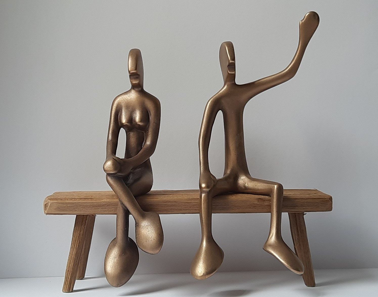 FRIENDsgirl No 11 und FRIEND No 2 - liebevolle Handarbeit in Bronze Zwei kleine Bronzefiguren von Bildhauer Oliver Pohl. Sie sitzen auf einem Holzpfahl. Im Hintergrund ist ein Strand an der Ostsee mit Meer und blauem Himmel zu sehen.