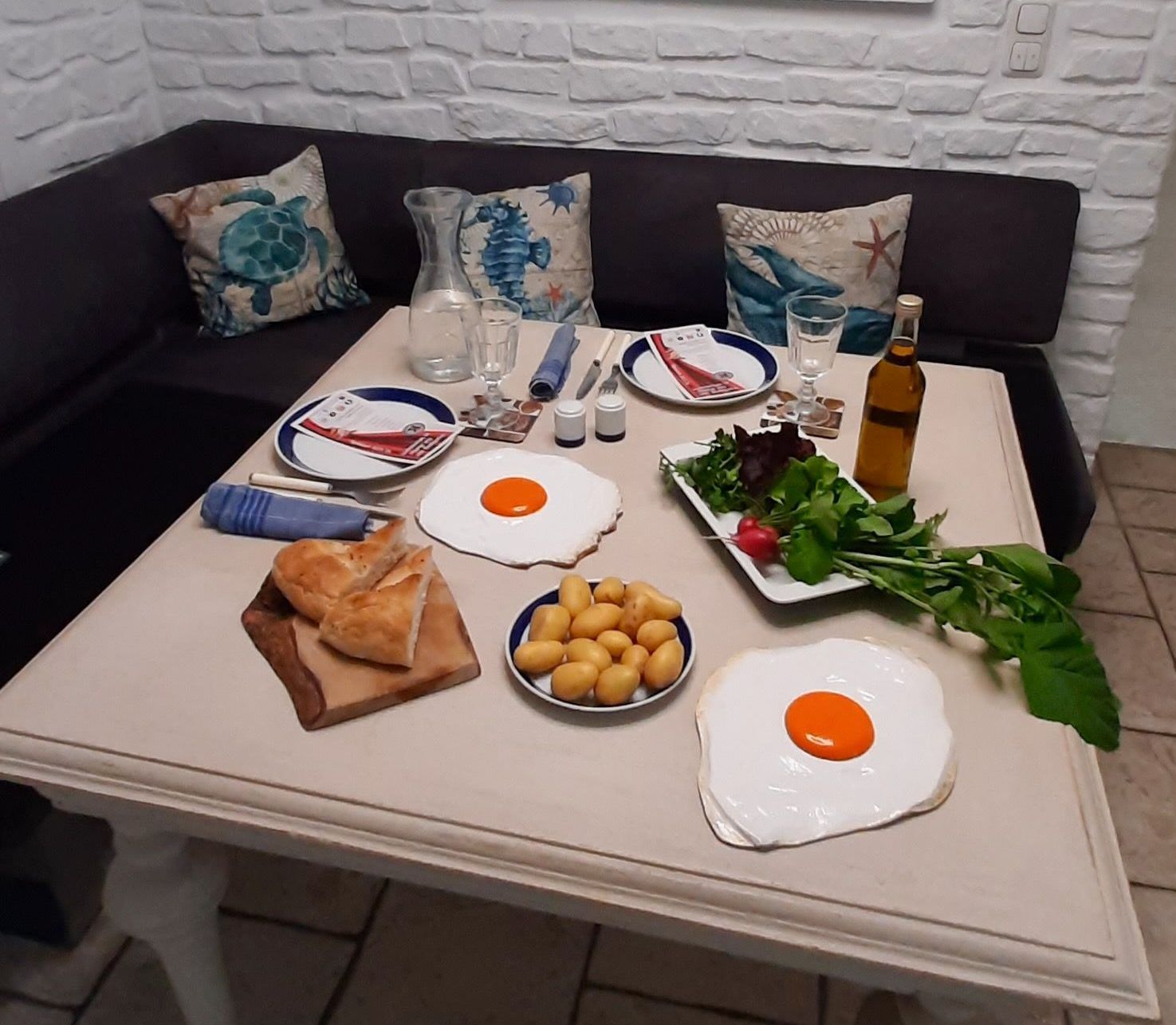 Das Bild zeigt einen geeckten Esstisch mit zwei Spiegleier Skulpturen von Bildhauer Oliver Pohl aus Haste im Schaumburger Land. Haste liegt in der Nähe zu Wunstorf.